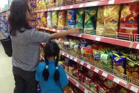 Een vrouw zoekt samen met haar dochter een zak buitenlandse chips uit in de supermarkt. Volgens Raymond Hasnoe van de Vereniging van Surinaamse Winkeliers (VSW), blijven buitenlandse producten tegenwoordig lang in de schappen staan. (Foto: Roy Bruce)